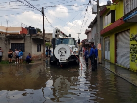 Vecinos y personal de bomberos laboran para desazolvar las coladeras